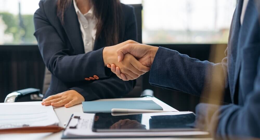 A business person shakes hands with their transaction advisory services partner.